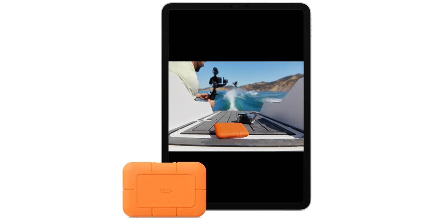Orange LaCie Rugged SSD in front of an iPad showing a filmmaker with a camera on a boat